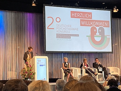 Hier sieht man Gesundheitsminister, Karl LAuterbach, am Mikrofon und Pult des Deutschen Psychotherapeutenkongresses in Berlin.